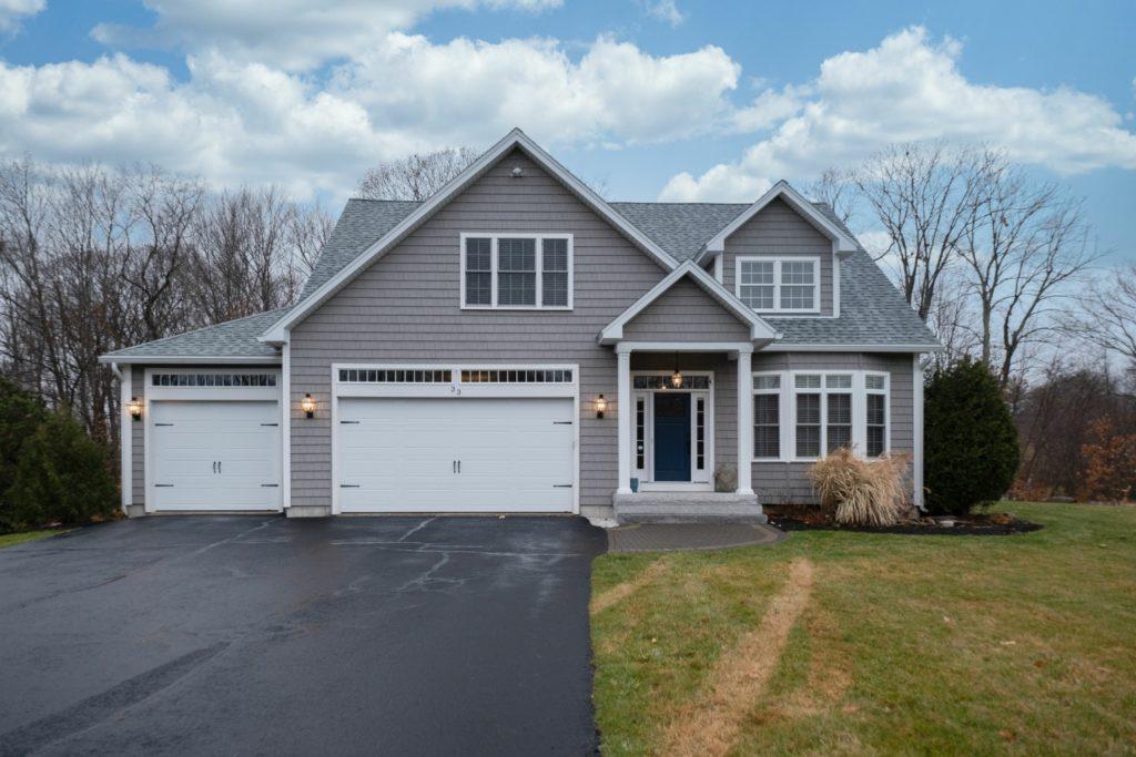 Gray-walled suburban house with white asphalt driveway